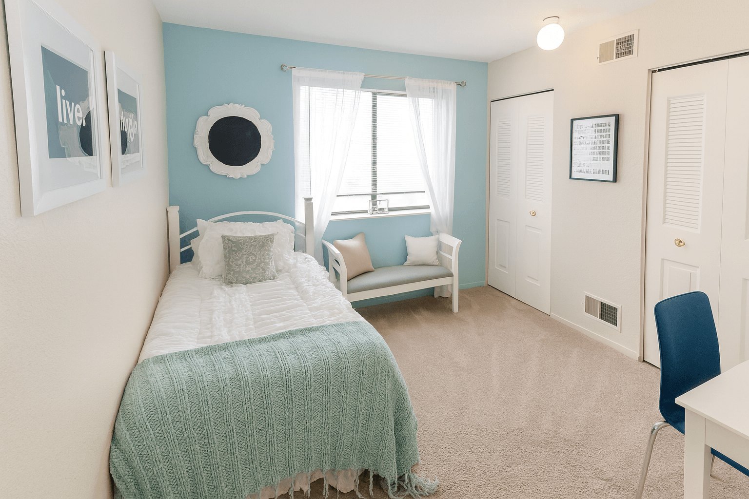 A bedroom with a bed, a chair, and a window.
